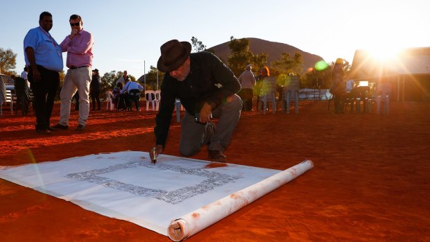 Indigenous leader Noel Pearson signs the canvas used for the Uluru Statement from the Heart's artwork in 2017.
