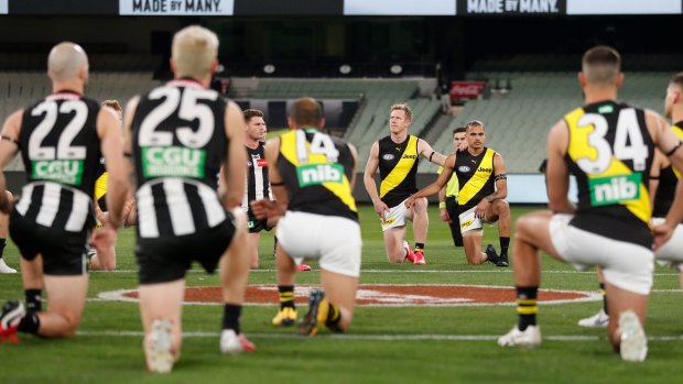 Players and umpires take the knee in support of the Black Lives Matter movement before the match between Collingwood and Richmond.