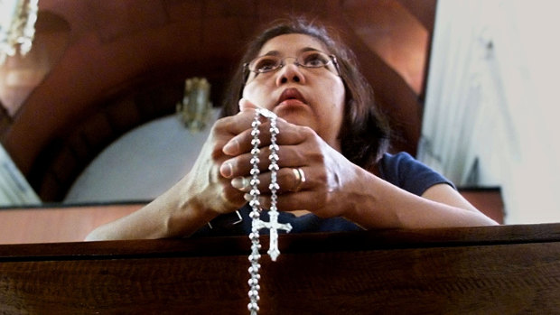 A Filipino woman prays at a catholic church.