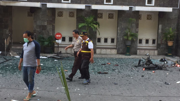 Officers walk past debris at Santa Maria church in Surabaya. 