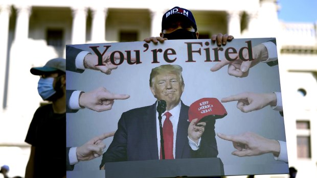 A supporter of President-elect Joe Biden holds a sign referring to President Donald Trump outside the Pennsylvania State Capitol, Saturday, Nov. 7, 2020, in Harrisburg, Pa., after Biden defeated Trump to become 46th president of the United States. 