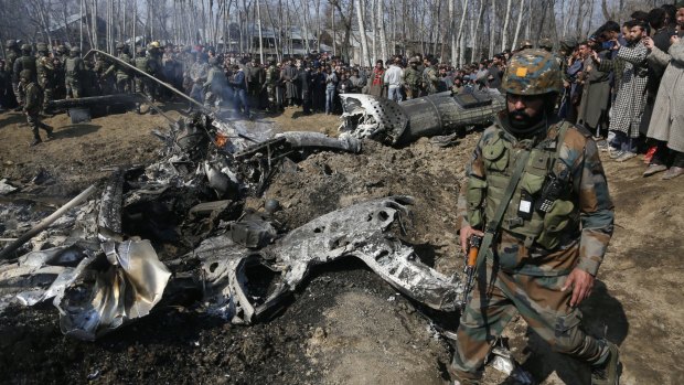An Indian army solider walks past the wreckage of an Indian aircraft after it crashed in the outskirts of Indian controlled Kashmir.