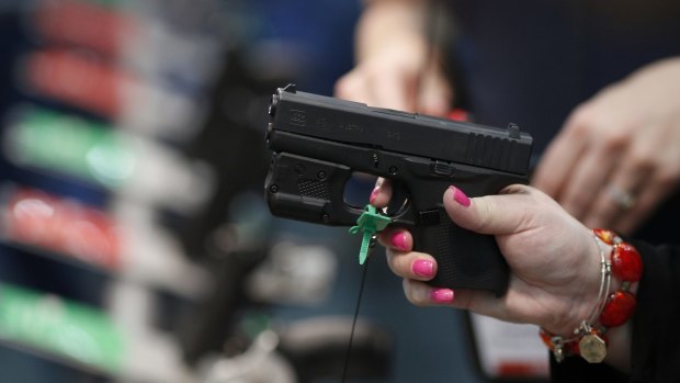 An attendee handles a firearm on the exhibit floor during the National Rifle Association (NRA) annual meeting in Louisville, Kentucky.