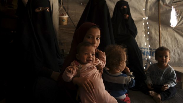 Nine-year-old Australian Maysa Assaad holds a baby in an al-Hawl camp tent. 