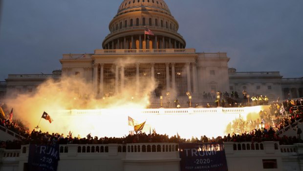 An explosion caused by a police munition is seen while supporters of US President Donald Trump gather in front of the US Capitol Building.