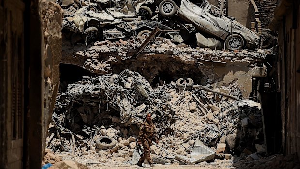 An Iraqi soldier walks past a wall of debris during the offensive to retake West Mosul in the northern summer of 2017.