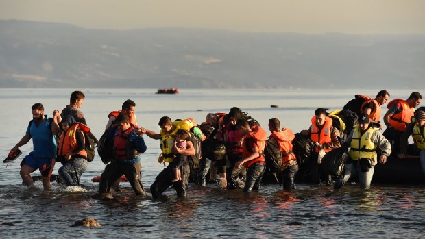 Refugees walk into the water as a boat with about 45 people from Syria, Iraq and Afghanistan aboard arrives at the Greek island of Lesbos after a three-hour journey from Turkey in 2015.