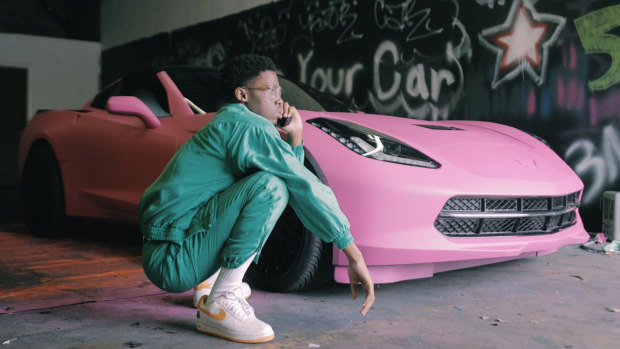 Shawn Cotton poses by his pink Corvette, purchased with profits he made as a videographer.