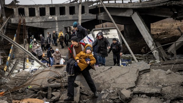 Residents of Irpin fleeing heavy fighting via a destroyed bridge as Russian forces enter the city on Monday.