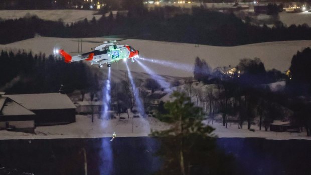 A person is lowered from a rescue helicopter near the site where a big landslide hit a residential area.