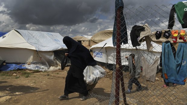 A woman walks past one of the gates of the foreign section of Al Hawl camp.