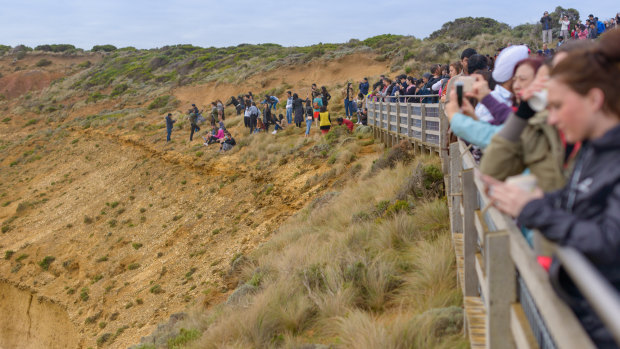Tourists pose for photos outside the designated viewing area for the Twelve Apostles at Port Campbell. 