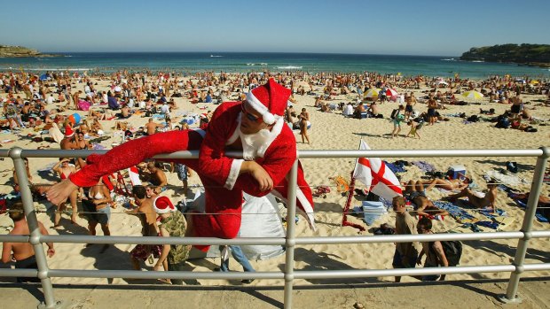 Santa Claus climbs down to the sand as crowds gather on Bondi Beach.