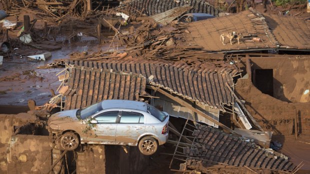 A car and two dogs are seen on the roof of destroyed houses in the small town of Bento Rodrigues after the Samarco dam collapse in 2015. 