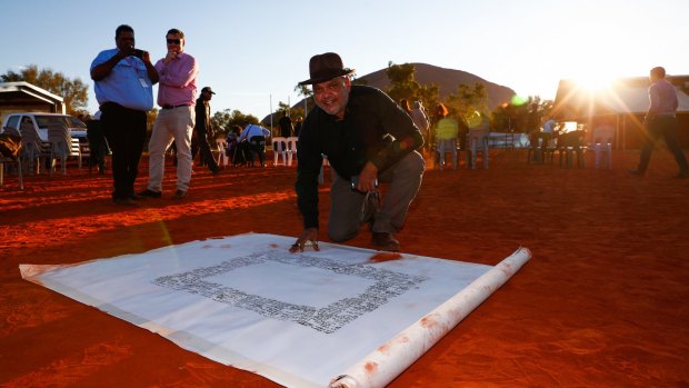 Noel Pearson signs the canvas upon which the Uluru Statement from the Heart will be painted. 