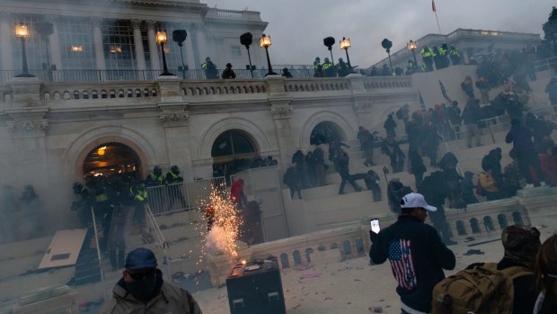 A flashbang grenade explodes as law enforcement officers push back demonstrators at the US Capitol building.