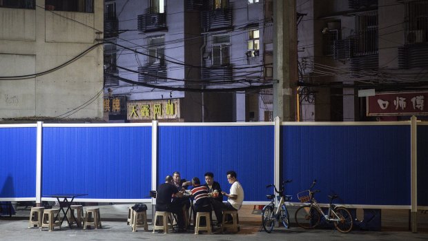 Residents eat next to a makeshift barricade built to control entry to a residential compound in Wuhan.