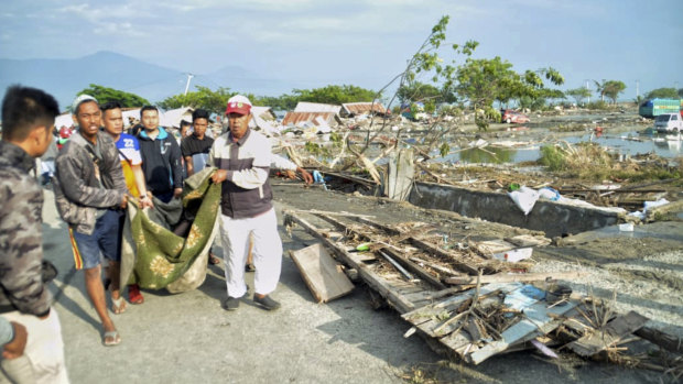 People carry the body of a tsunami victim in Palu.