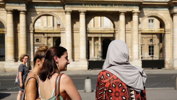 A woman wearing a Muslim headscarf, right, and who refused to be identified, stands outside the Conseil d'Etat, France's top administrative court, in Paris. The court overturned a town burkini ban in 2016.