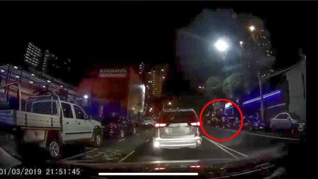 A screenshot from the dashcam footage. A group of people are seen outside the boxing venue. 