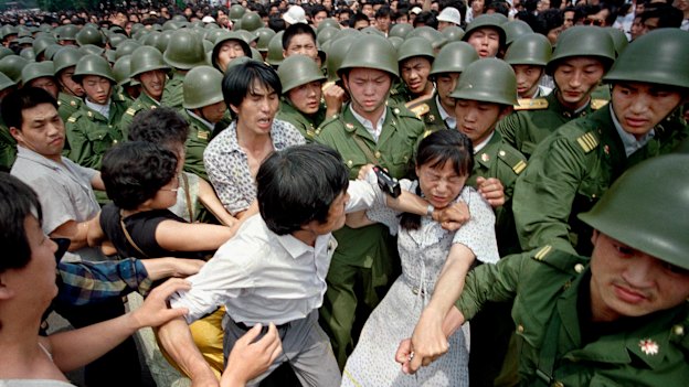 A young woman is caught between civilians and Chinese soldiers, who were trying to remove her from an assembly near the Great Hall of the People the day before the massacre.