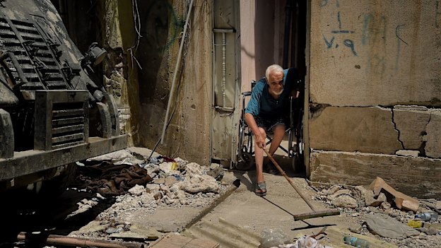 Abdulsalam Abdulqadir, 73, sweeps outside his gate from his wheelchair as an air strike hits nearby in West Mosul, Iraq, in October 2017.
