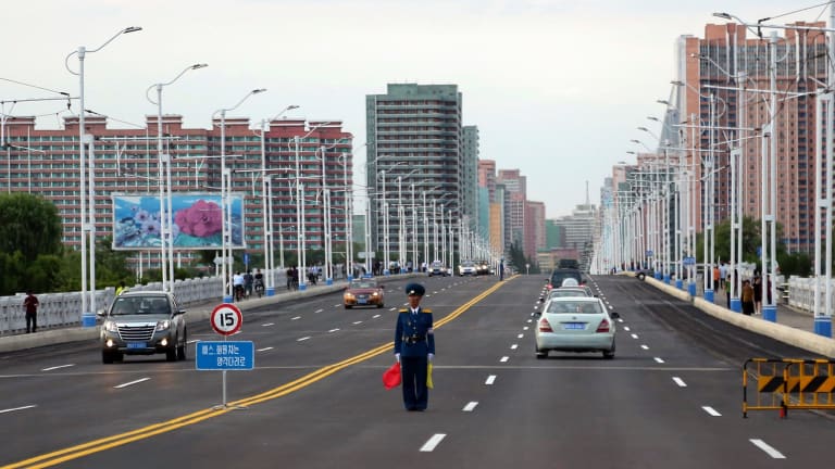 A police man directs traffic on a street lined with apartment buildings in Pyongyang.