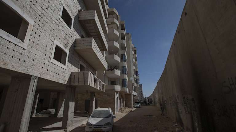 A building under construction in the Kufr Aqab neighbourhood in Jerusalem, divided from the rest of the city by Israel's security barrier, seen on the right.