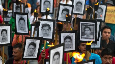 Family members of 43 missing teacher's college students carry pictures of the students in a 2016 protest against closing the case.