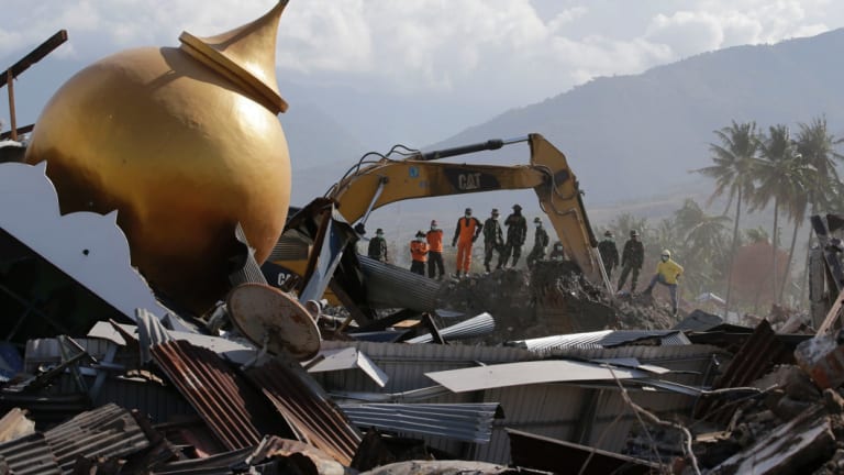 Rescuers stand beside a toppled mosque as recovery efforts continue in the earthquake-hit Balaroa neighborhood in Palu, Central Sulawesi, Indonesia.