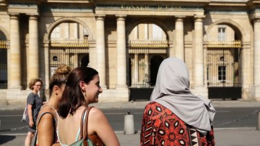 A woman wearing a Muslim headscarf, right, and who refused to be identified, stands outside the Conseil d'Etat, France's top administrative court, in Paris. The court overturned a town burkini ban in 2016.