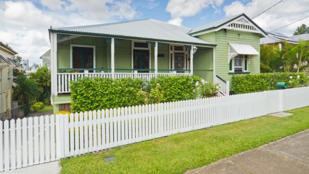 Tradition Queenslander house in light green with hedge