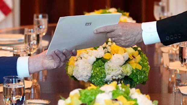 Israel’s Prime Minister Benjamin Netanyahu, right, hands President Donald Trump a folder during a meeting in the Blue Room of the White House, Monday, July 7, 2025, in Washington. (AP Photo/Alex Brandon)