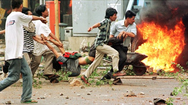 Student protesters carry a man shot by police during riots on May 14, 1998. 