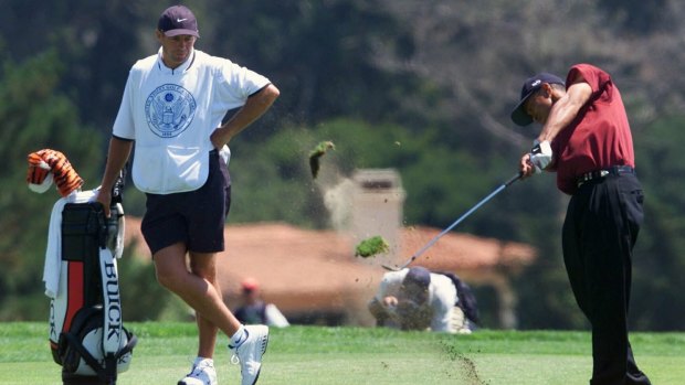 Steve Williams watches on as Tiger Woods hits on the 11th green at Pebble Beach in 2000.
