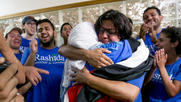 Rashida Tlaib embraces her mother Fatima Elabed, who wears a Palestinian flag across her shoulders, in Detroit after Tlaib won the Democratic primary race on August 7.