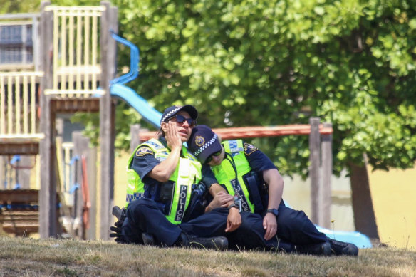 Police officers comfort each other at the scene of a tragic jumping castle accident at Hillcrest Primary School in Devonport that left five children dead. 
