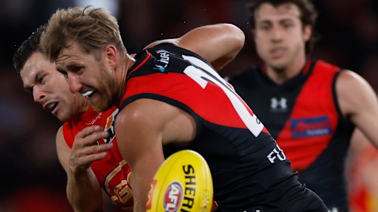 Essendon’s Dyson Heppell clashes with Gold Coast’s Ben Ainsworth before he was subbed out of the game.