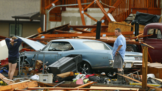 A man and woman inspect the damage to their home and classic cars after a tornado hit Kansas. 