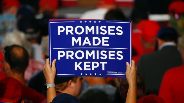 Promises to keep - even if they're not based in reality. Supporters hold up signs as the wait to hear President Donald Trump speak at a campaign rally in Florida in November.