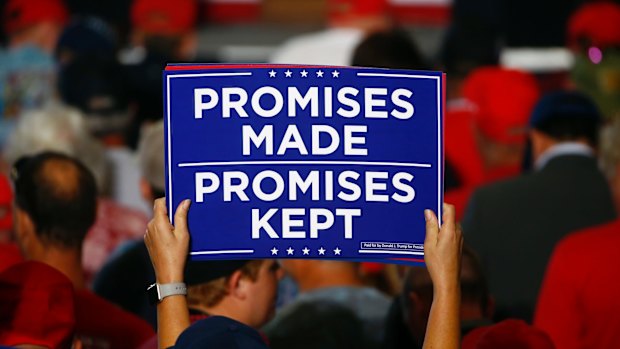 Promises to keep - even if they're not based in reality. Supporters hold up signs as the wait to hear President Donald Trump speak at a campaign rally in Florida in November.