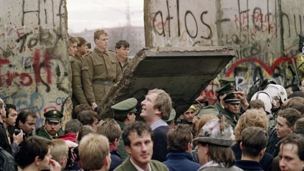 West Berliners watch East German border guards demolishing a section of the wall on November 11, 1989.