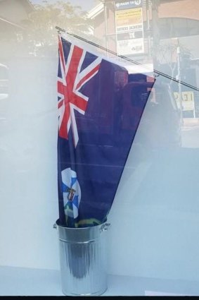 The Queensland flag being lowered into a rubbish tin of bleach symbolises the state losing its life, the artists say.