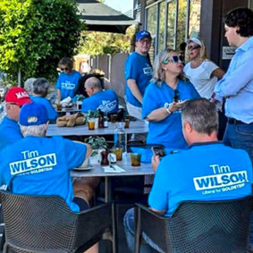 Tim Wilson supporters gathering in a Melbourne cafe, with one sporting a purported MAGA cap.