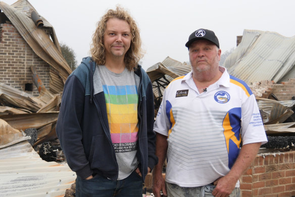 Kyle Moser, left, and his partner David Wilson, in front of the ruins of their Cobargo home.
