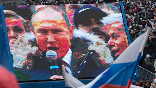 Attendees wave Russian national flags in support of Vladimir Putin, Russia's President, as he speaks on screen during a pre-election rally at Luzhniki stadium in Moscow, Russia in March. 