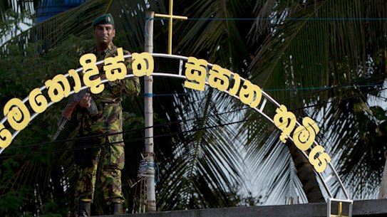 An officer of the Sri Lankan Special Task Force stands guard atop a building as funerals of Easter Sunday bomb blast victims take place at the Methodist burial ground in Negombo, 