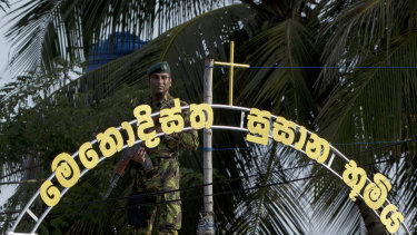 An officer of the Sri Lankan Special Task Force stands guard atop a building as funerals of Easter Sunday bomb blast victims take place at the Methodist burial ground in Negombo.