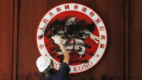 A protester defaces the Hong Kong emblem after breaking into the Legislative Council building on July 1, 2019. Protesters took over the legislature's main building, tearing down portraits of legislative leaders and spray painting pro-democracy slogans on the walls of the main chamber.
