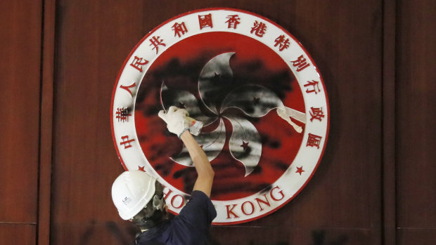 A protester defaces the Hong Kong emblem after breaking into the Legislative Council building on July 1, 2019. Protesters took over the legislature's main building, tearing down portraits of legislative leaders and spray painting pro-democracy slogans on the walls of the main chamber.